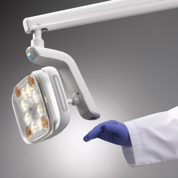 A gloved hand using the touchless on/off sensor on the A-dec 500 LED dental light